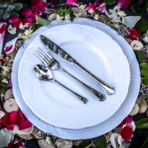 Assiettes Pya avec les couverts, sur une table de mariage fleurie